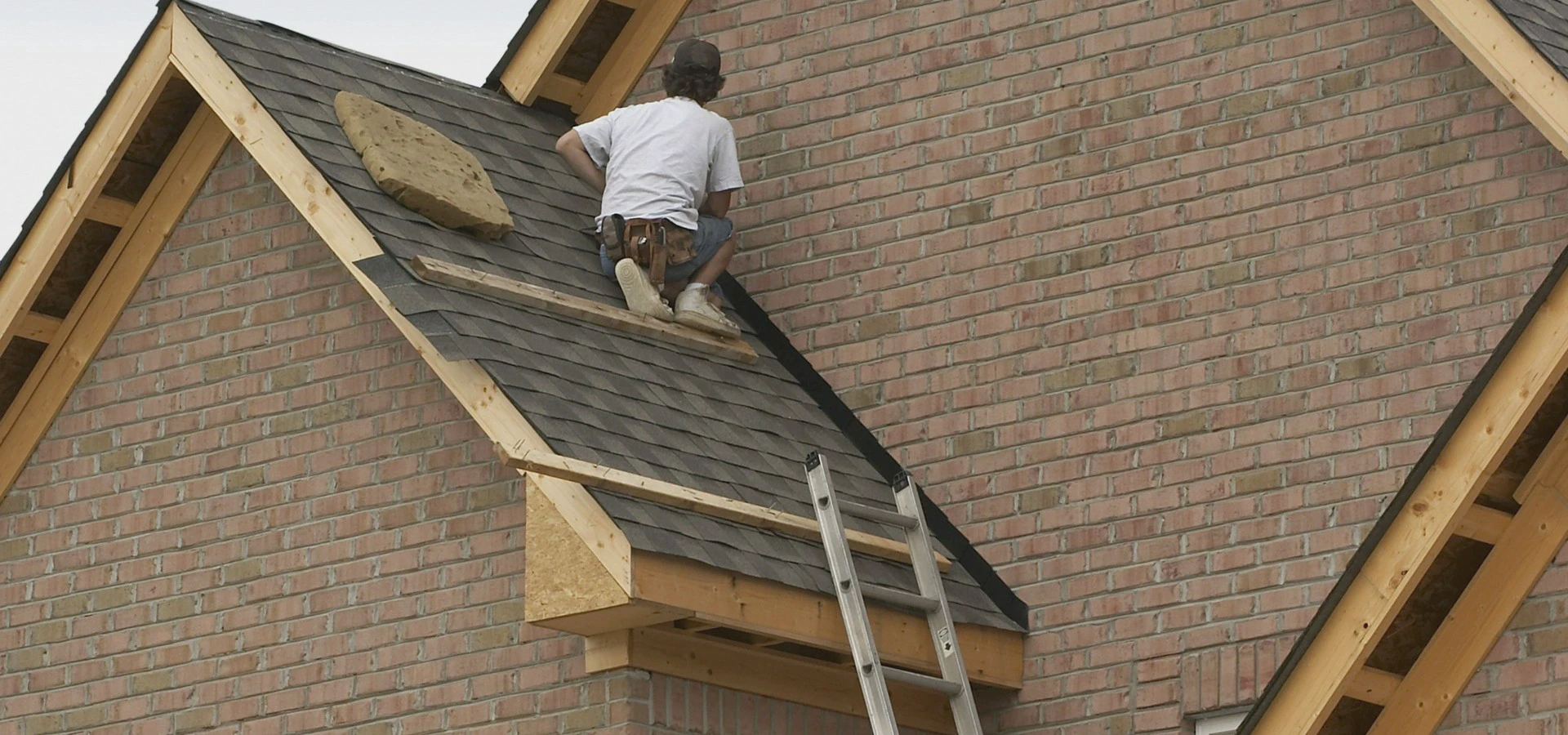Montaż pokrycia dachowego podczas prac dekarskich na&nbsp;budynku z&nbsp;cegły